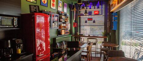Un bar de estilo retro con electrodomésticos antiguos, un jukebox y un letrero de neón.