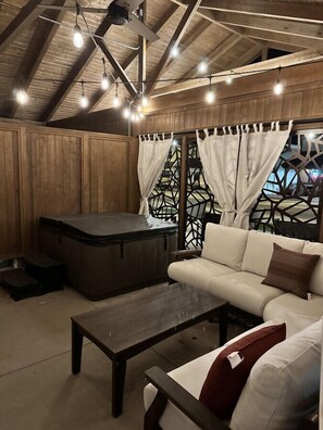 A cozy room with a wooden ceiling, a sofa, a coffee table, and a hot tub. - Romantic Getaway with Private Patio and Hot Tub on Main Street - Maple Suite (Berlin)