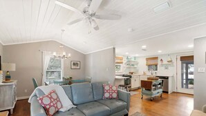 A spacious living room with a grey sofa, wooden coffee table, and a ceiling fan. - Tutti Frutti (Santa Rosa Beach)