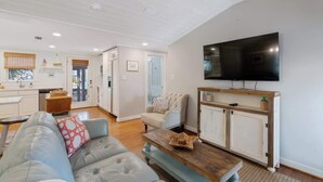 A spacious living area with a sofa, coffee table, and a television mounted on the wall. - Tutti Frutti (Santa Rosa Beach)