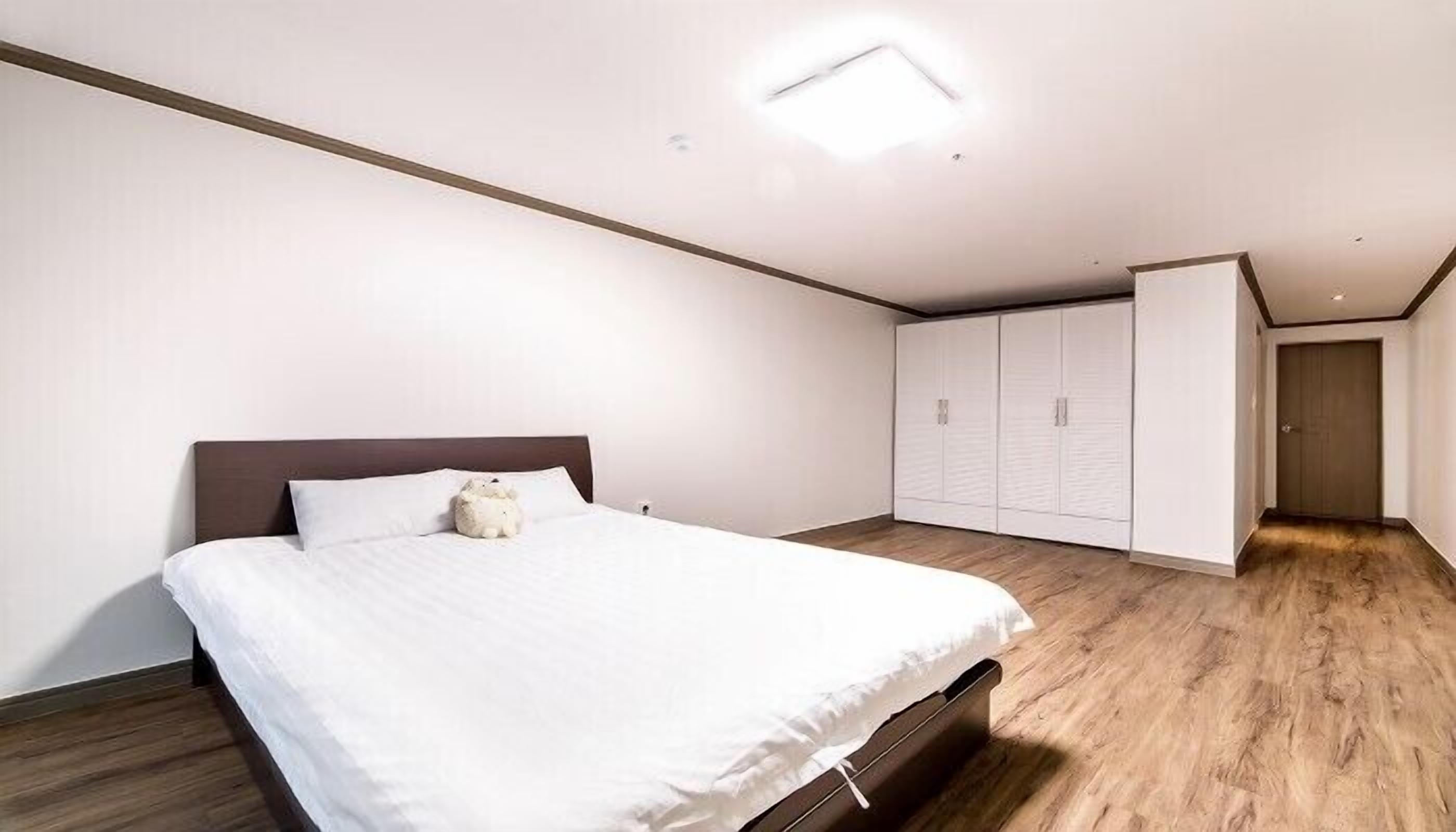 A bedroom with a bed, a nightstand, a wardrobe, and a door.