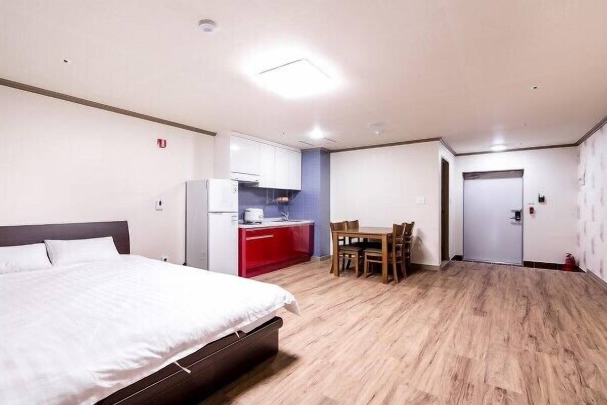 A hotel room with a bed, a kitchenette, a dining table, and a door.