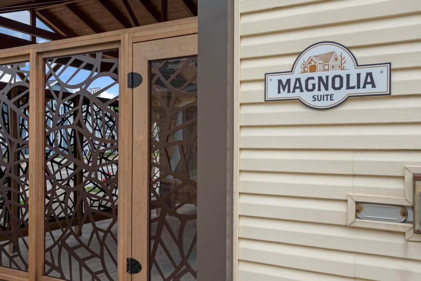 Una puerta de madera con un diseño geométrico y un letrero que indica la Suite Magnolia en un edificio.