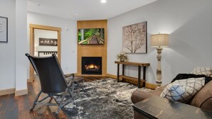 A living room with a fireplace, a black leather chair, a sofa, and a coffee table.