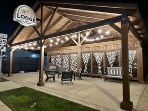 A covered outdoor seating area with string lights, wooden furniture, and a sign reading "Main Street Lodge 4792".