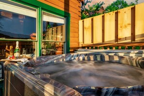 A hot tub area with a wooden deck, a glass door, and a view of the outdoors. - Updated Cabin | Amazing Views,Hot Tub,Location (Sevierville)