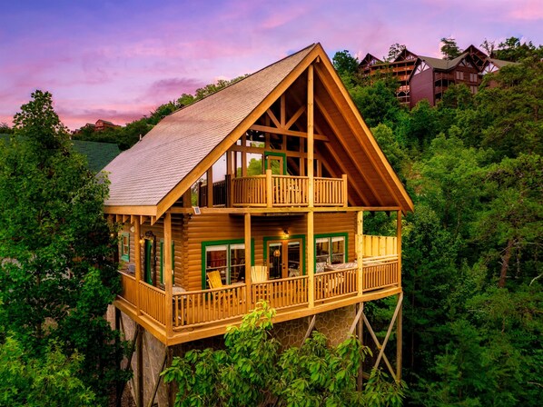 A wooden cabin with a balcony, surrounded by lush greenery. - Updated Cabin | Amazing Views,Hot Tub,Location (Sevierville)