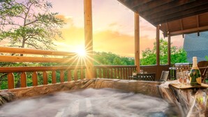 A hot tub with a wooden deck and a sunset view. - Updated Cabin | Amazing Views,Hot Tub,Location (Sevierville)