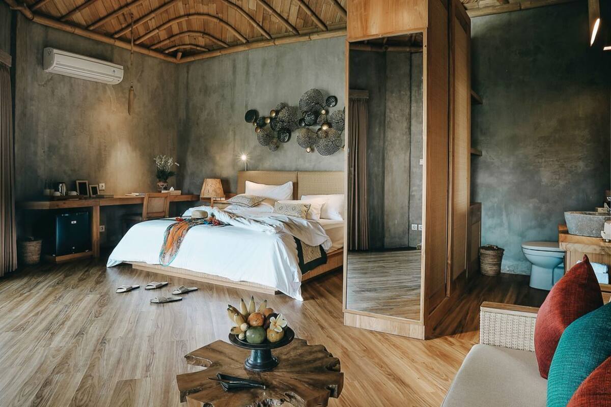 A spacious room with a high wooden ceiling, a large bed, a dining area, and a small kitchen.