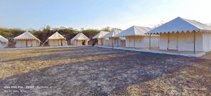 A row of white tents with a gravel ground, arranged in a linear fashion.