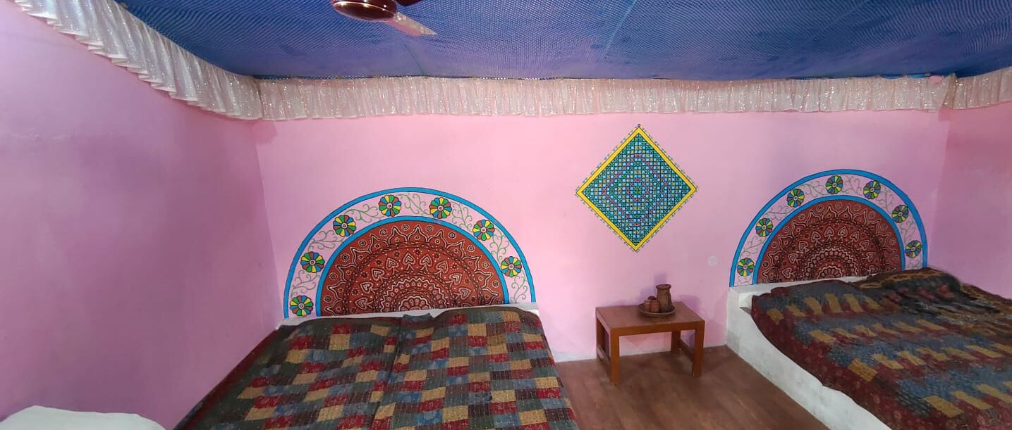A room with two beds, a small table, and decorative wall patterns.