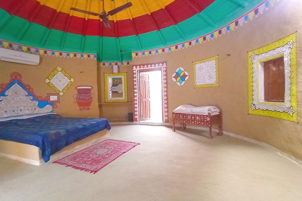 A bedroom with a bed, a small table, a door, and a ceiling fan.