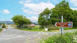 Un camino rural con un cartel que indica el campamento de Cultybraggan.