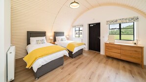 Un dormitorio con dos camas, un aparador, una ventana con vistas y una puerta.
