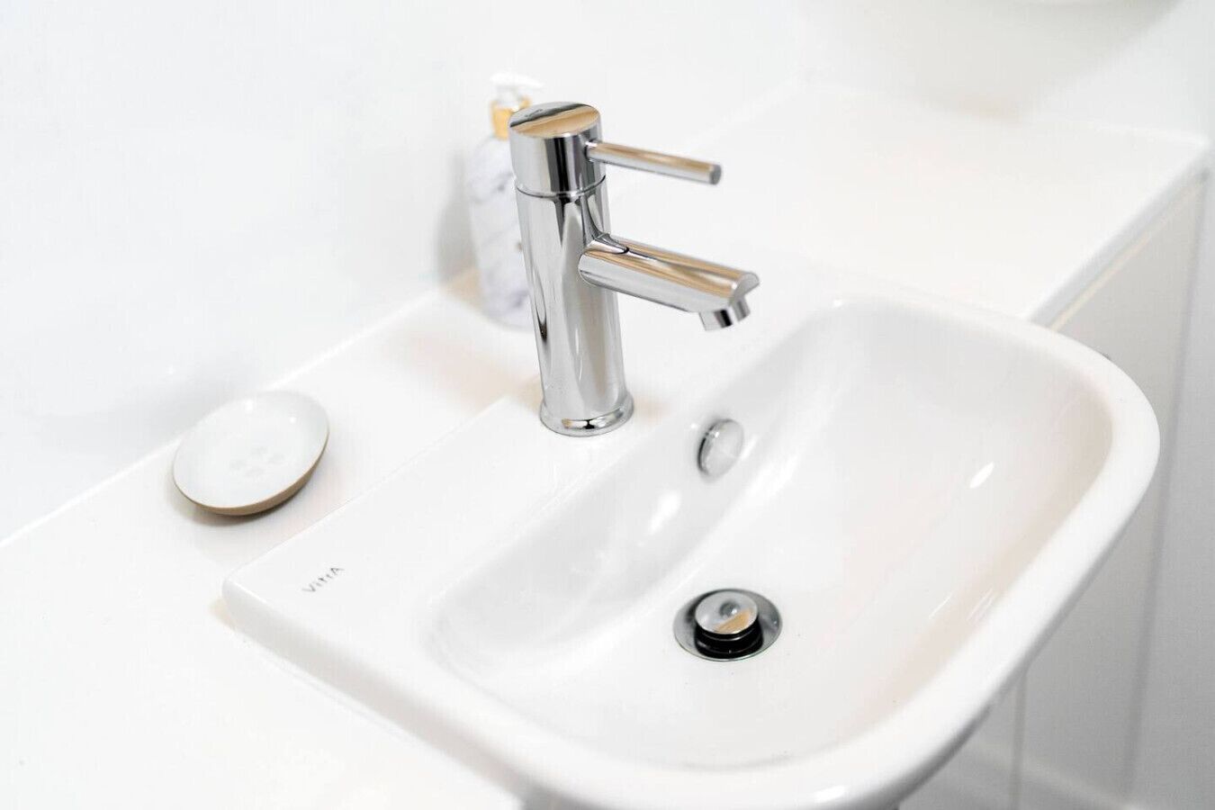 A white bathroom sink with a chrome faucet and a soap dish.