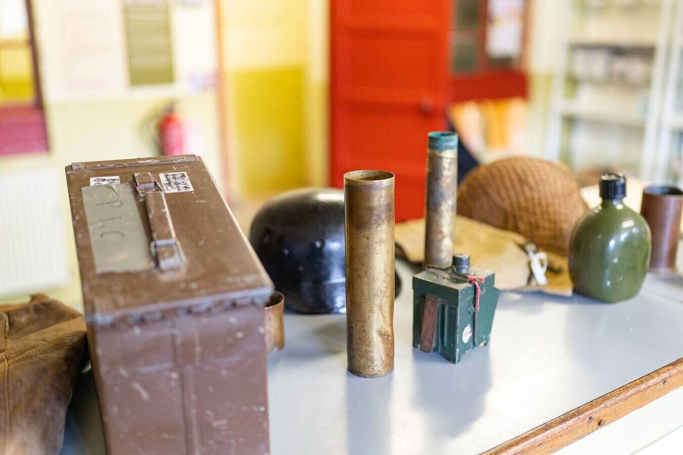 Diverse oudigheden op een tafel, waaronder een bruine doos, een cilindervormig voorwerp, een groene fles en een zwarte houder.