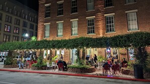 A brick building with outdoor seating and string lights.