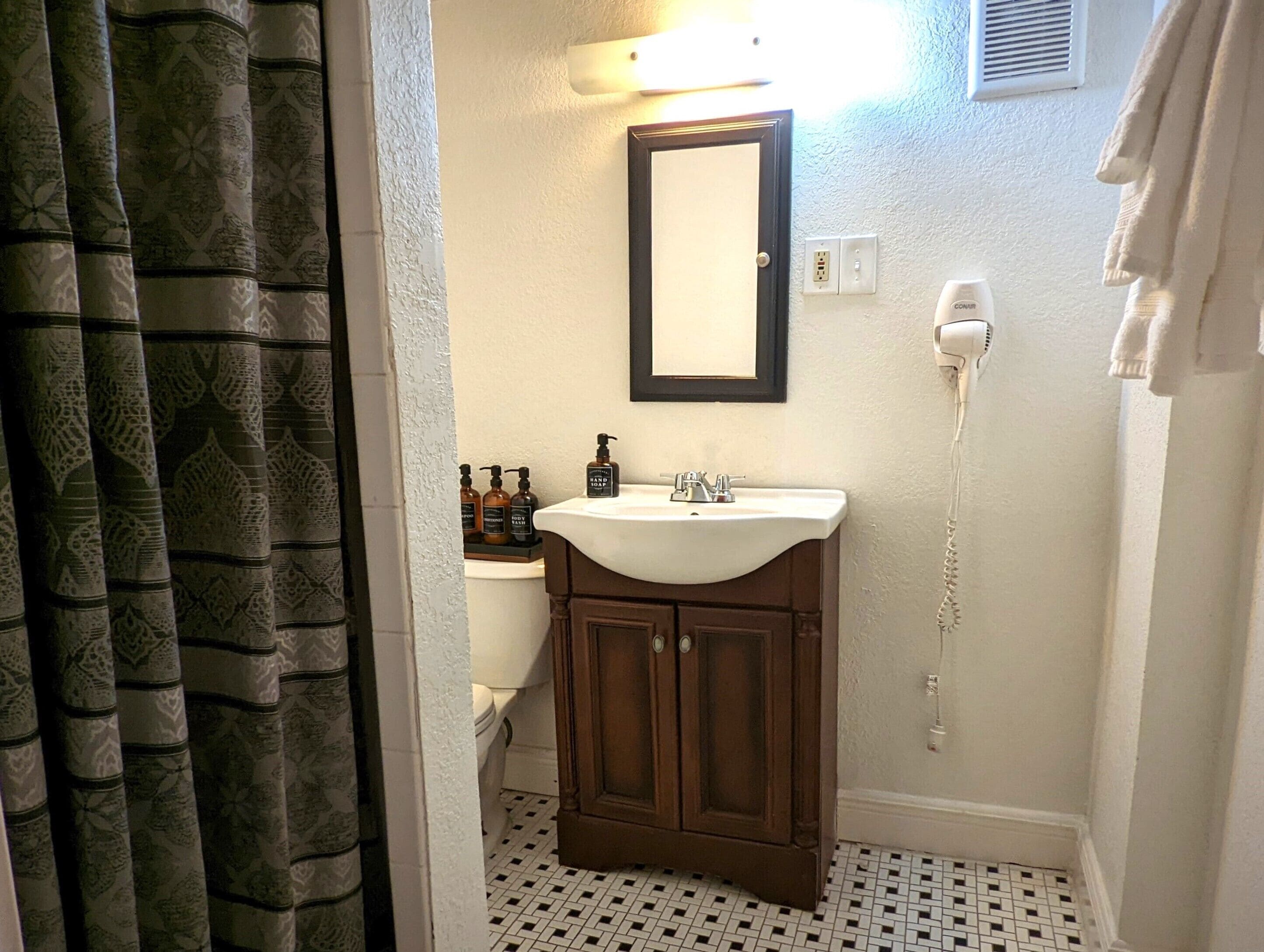 Un bagno con un lavandino bianco, uno specchio e un asciugacapelli a parete.