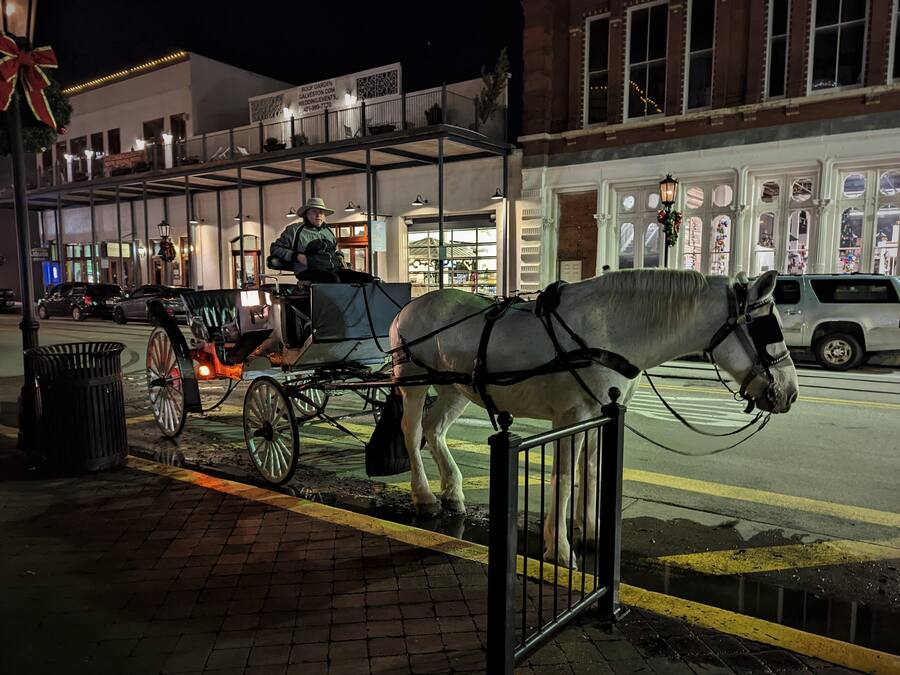 A horse-drawn carriage on a city street at night.