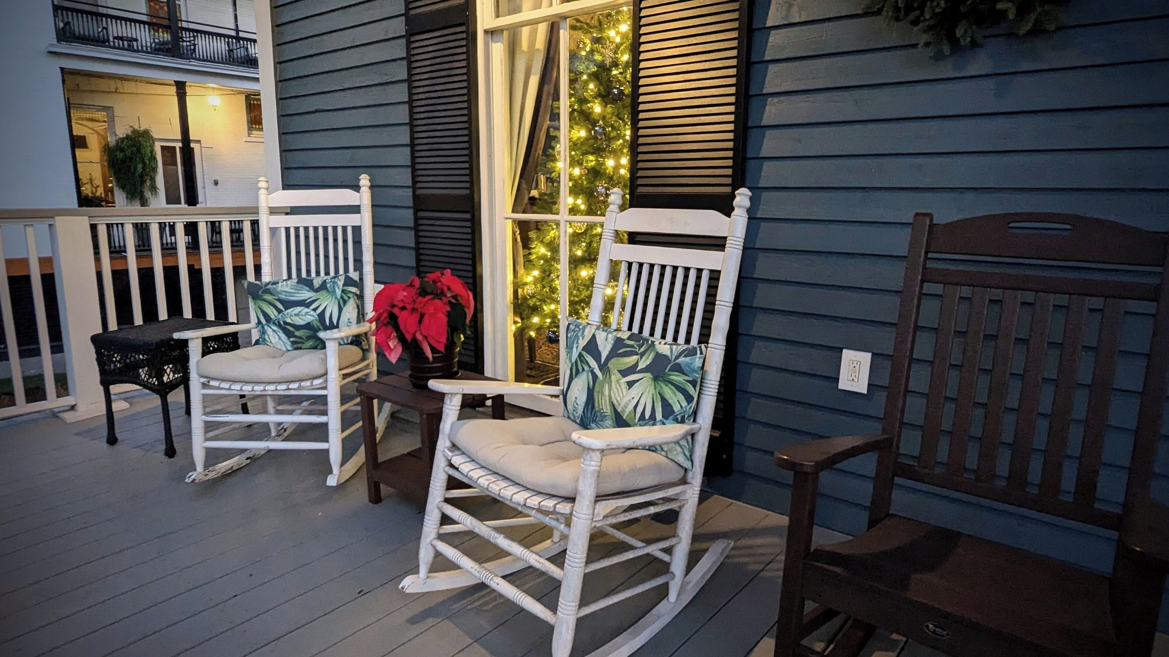 A porch with two rocking chairs, a small table, and a potted plant.