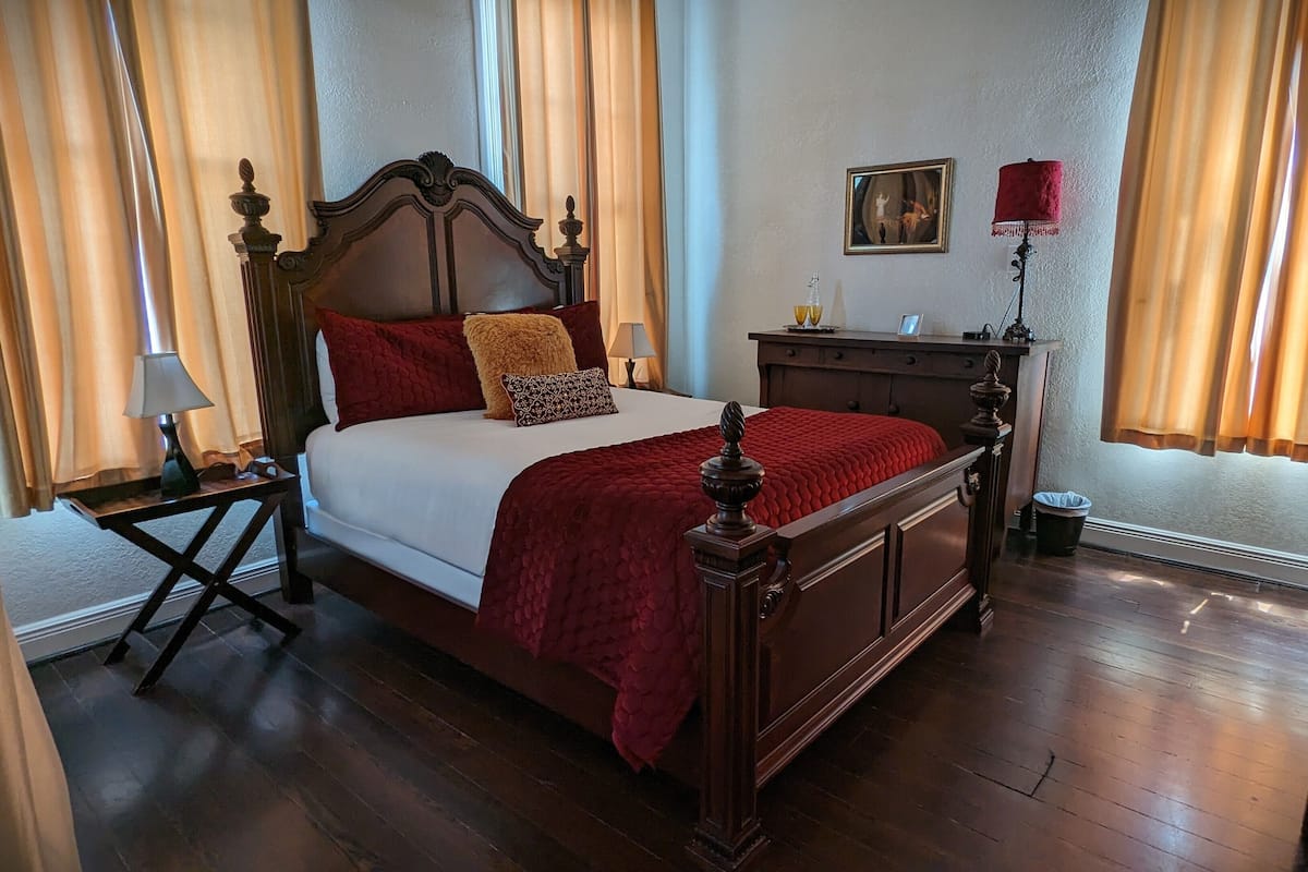 A neatly arranged bedroom with a wooden bed, a nightstand, a dresser, and a lamp.