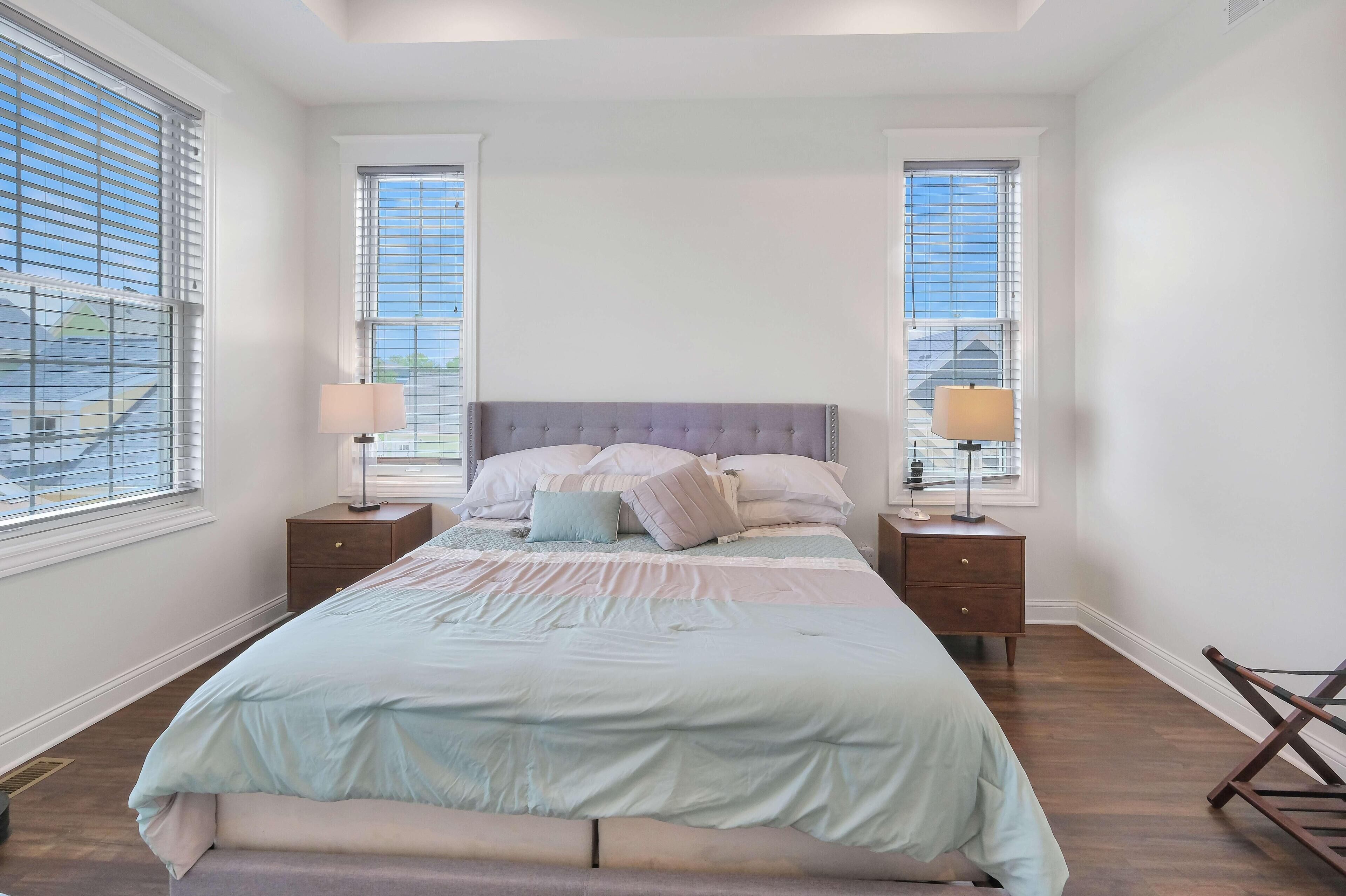 Een slaapkamer met een groot bed, twee nachtkastjes en een houten stoel.