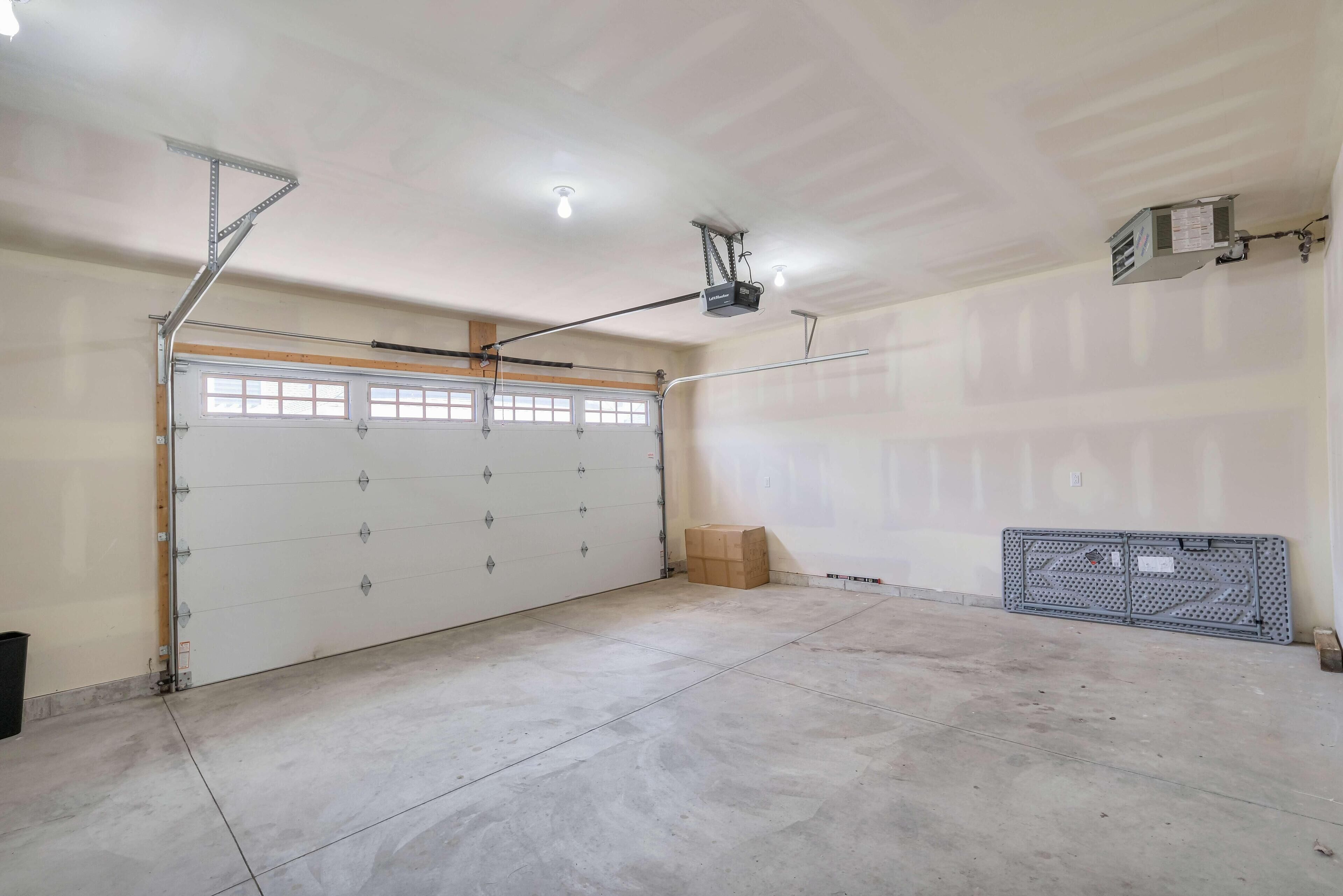 A garage with a white garage door, a ceiling-mounted projector, and a metal workbench.