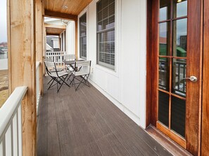 A covered porch with a table and chairs, large windows, and a wooden door. - Blue Dog Landing (Ottawa)