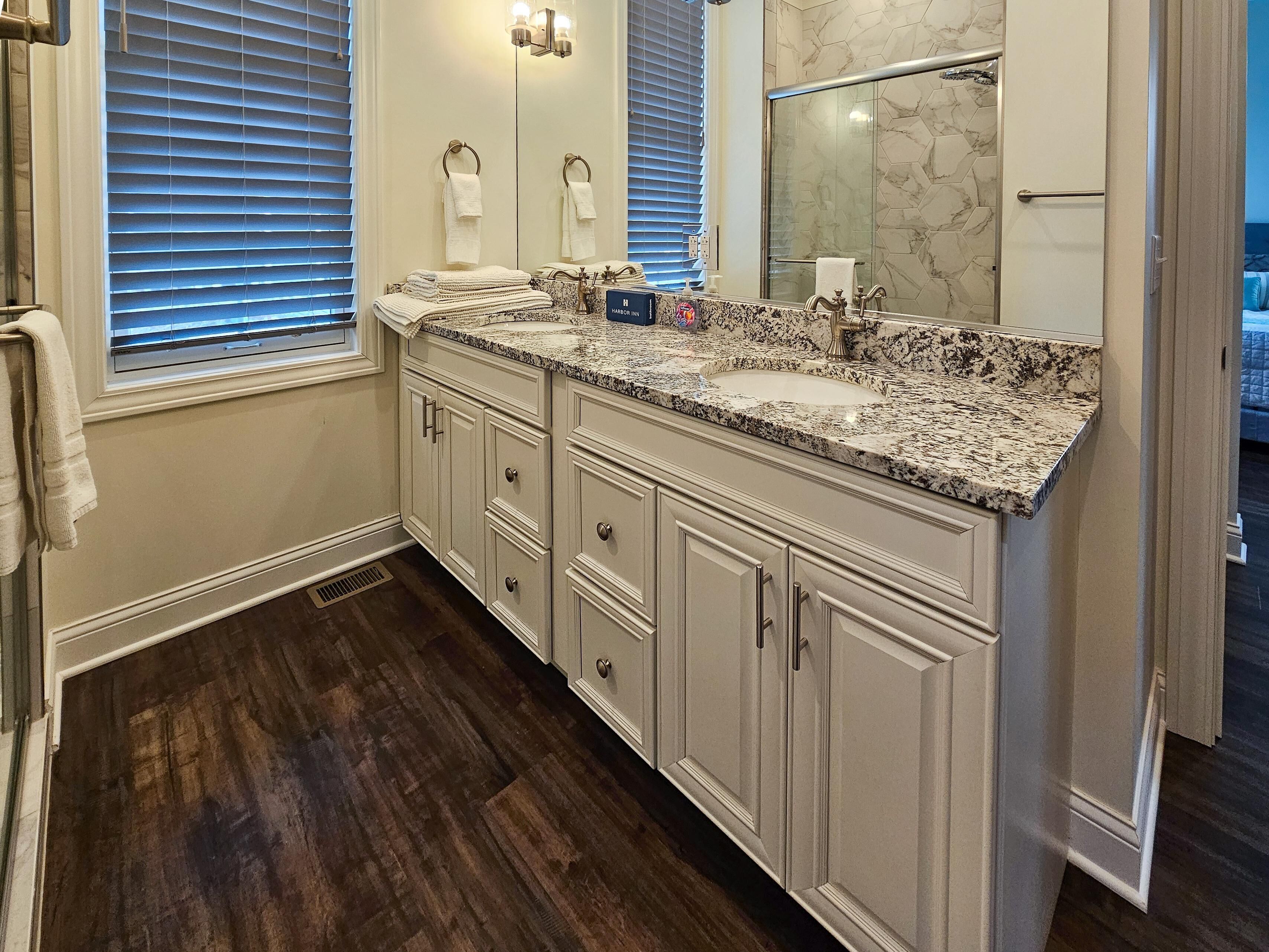 A bathroom with a marble sink, double vanity, and a large mirror.