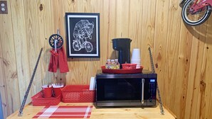 A kitchen counter with a microwave, a red basket, and a framed picture of a bull on a bicycle. - Tour de Bison Cabin Cache near Wichita Mountains Cycling Biking Cache sleeps 4 (Cache)