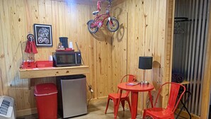 A compact kitchen with a microwave, refrigerator, and a hanging bicycle. - Tour de Bison Cabin Cache near Wichita Mountains Cycling Biking Cache sleeps 4 (Cache)