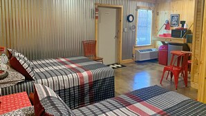 A room with two beds, a chair, a desk, a window, and a door. - Tour de Bison Cabin Cache near Wichita Mountains Cycling Biking Cache sleeps 4 (Cache)