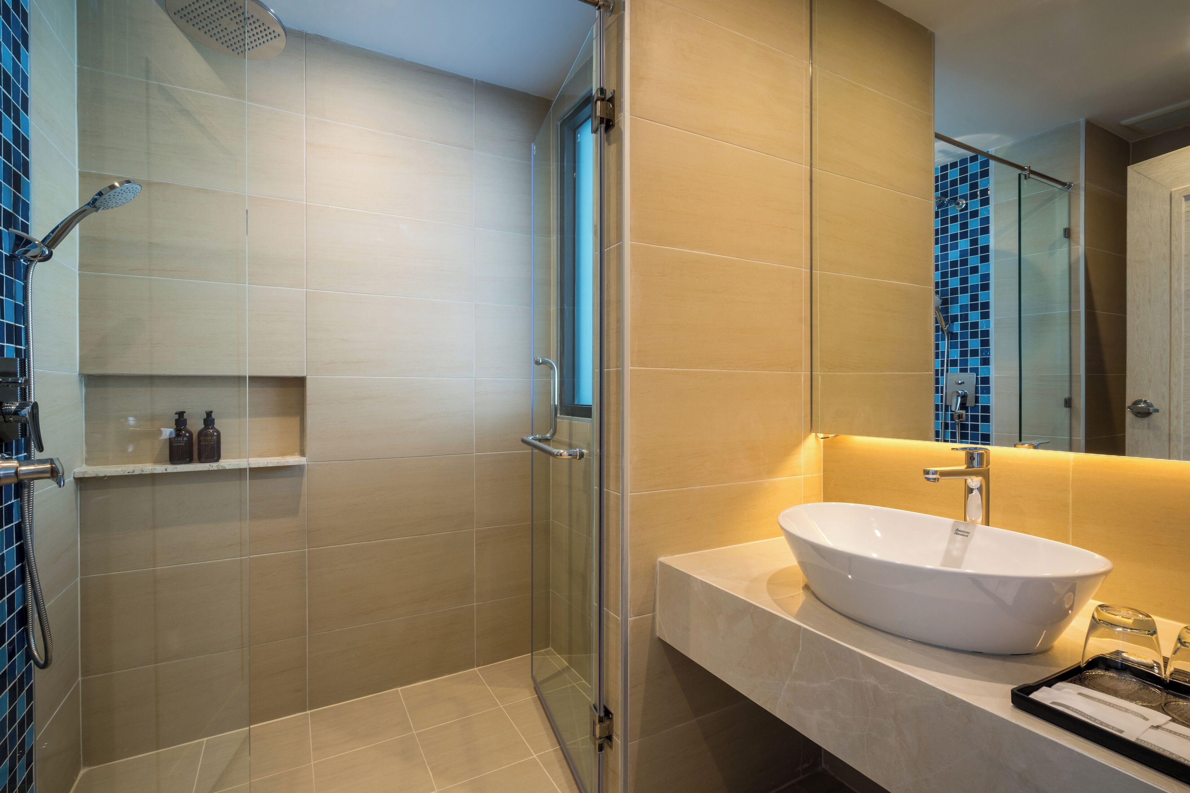 Un baño moderno con ducha de vidrio, un lavamanos blanco y un espejo sobre él.