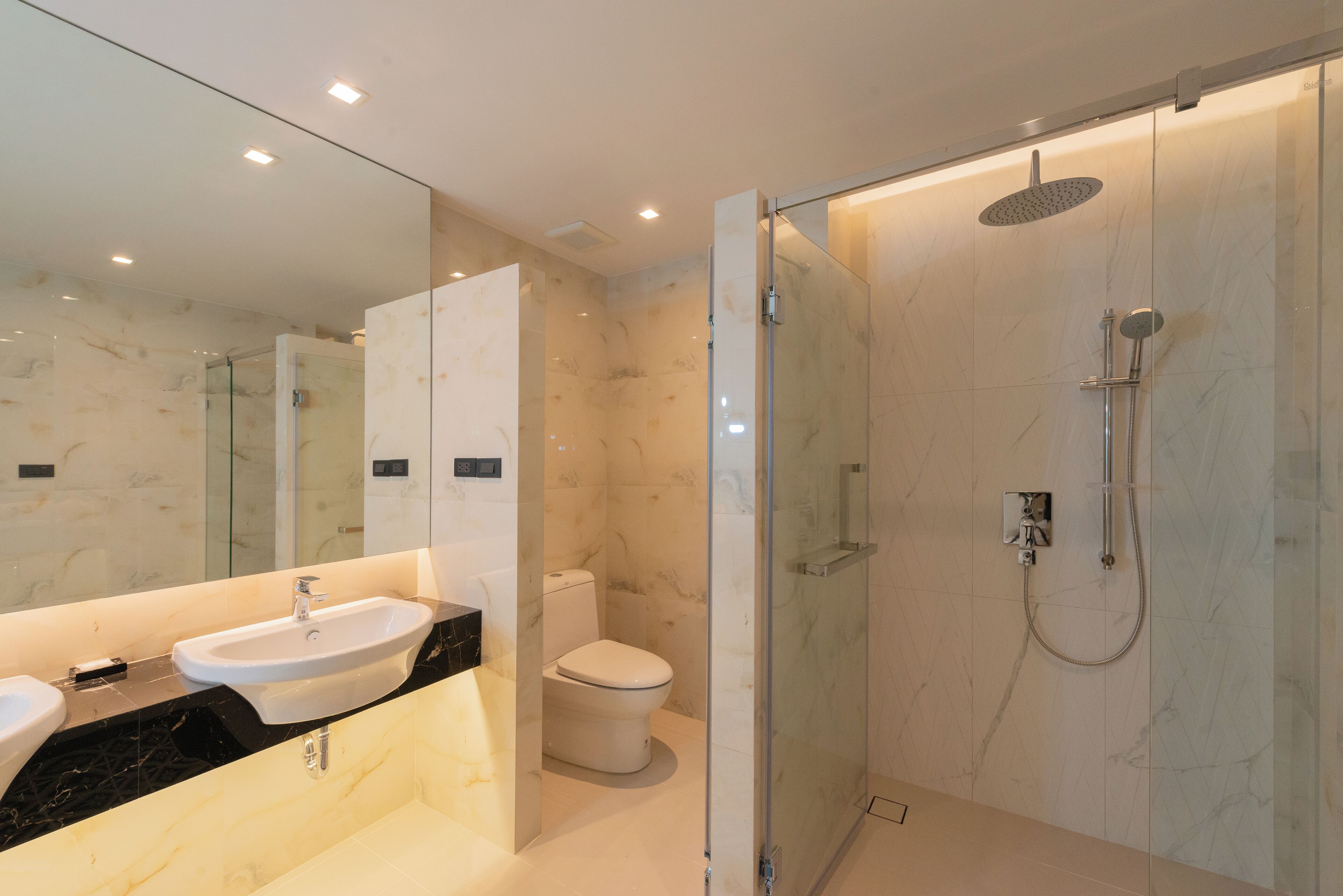 A modern bathroom with a glass-enclosed shower, a sink, and a toilet.