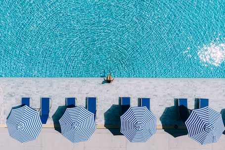 Una piscina al aire libre, sombrillas, sillones reclinables de piscina