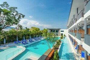 A modern hotel with a swimming pool, lounge chairs, and a view of the sea. - Seabed Grand Hotel Phuket (Wichit)