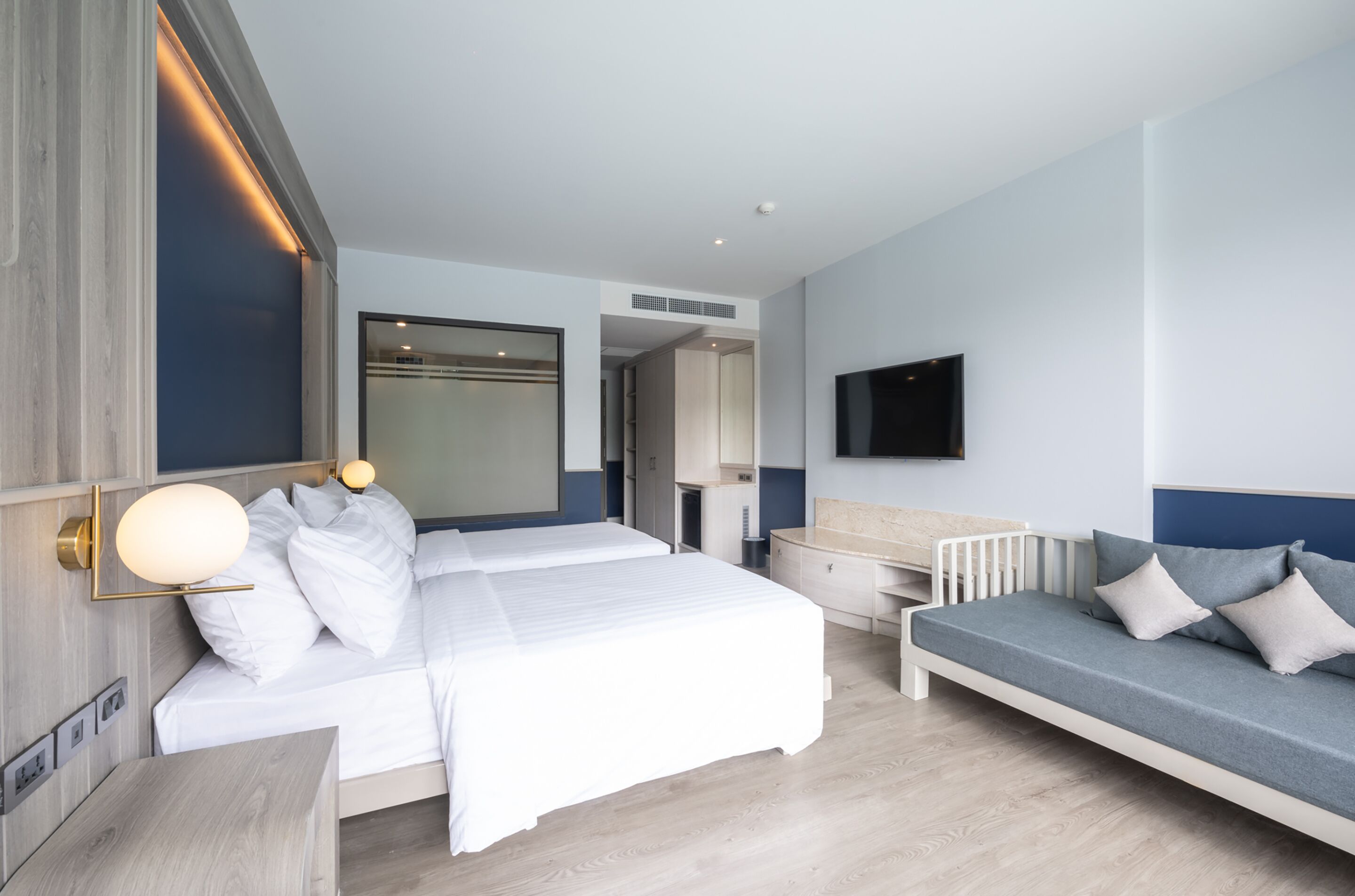 Ein modernes Hotelzimmer mit einem großen Bett, einem Schlafsofa, einem Fernseher und einem Schreibtisch.