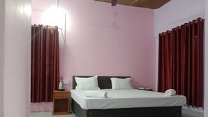 Un dormitorio con cama, mesita de noche, lámpara y cortinas rojas.