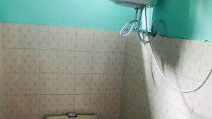 Un baño pequeño con inodoro, calentador de agua montado en la pared y paredes con azulejos.