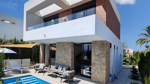 Ein modernes, zweistöckiges Haus mit Swimmingpool, Außenbereich und einer Fassade aus Stein.