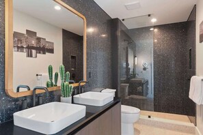 A modern bathroom with two sinks, a large mirror, and a shower area.