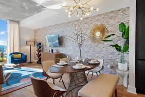 A modern dining area with a round table, chairs, and a decorative wall piece.