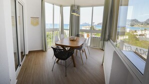 A dining area with a wooden table, chairs, and a view of the sea. - A77 HERNANDO I 3º - G (Calpe)
