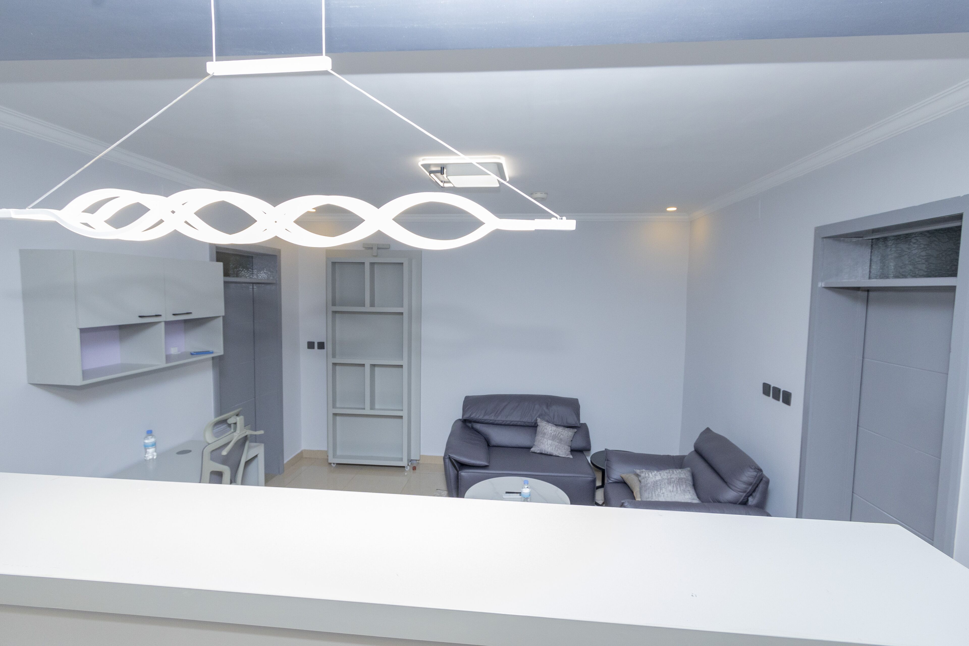 A modern, minimalist room with a grey sofa, a small round table, and a pendant light.