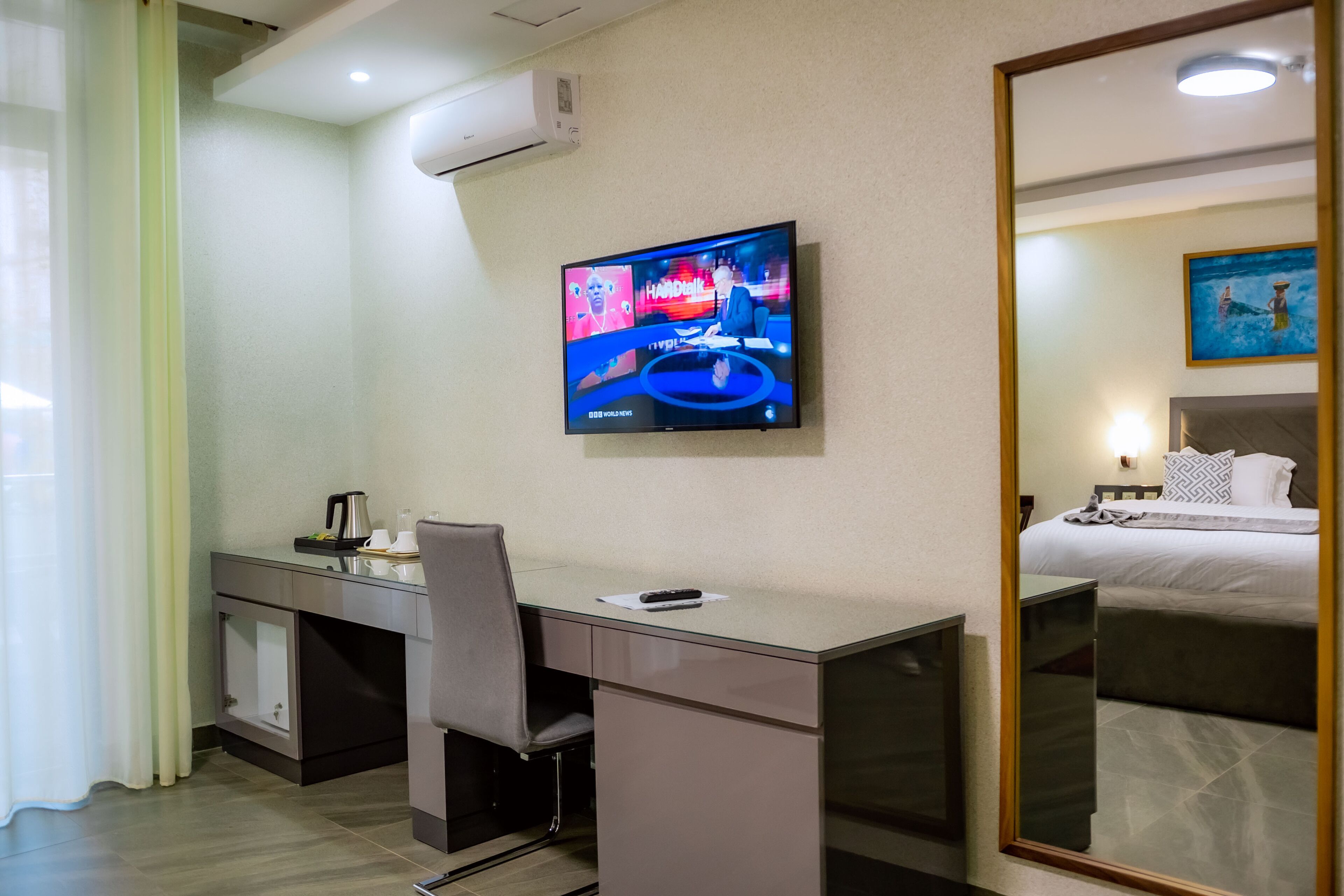 Habitación de hotel con escritorio, silla, cama y televisor montado en la pared.
