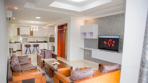 Ein modernes Wohnzimmer mit einer Sofagarnitur, einem Couchtisch und einem an der Wand befestigten Fernseher.