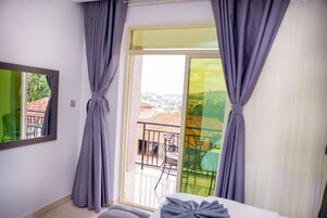A hotel room with a balcony, a bed, a chair, and a table.