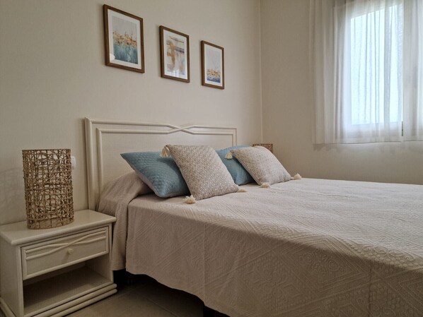 Un dormitorio ordenado con cama, mesita de noche y obra de arte colgada en la pared.
