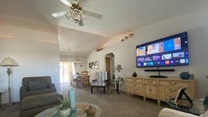 Ein Wohnzimmer mit Fernseher, Sofa, Couchtisch und Deckenventilator.