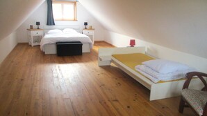 Un petit appartement d’une seule pièce, avec un plafond de style industriel, un lit, une chaise et une table de chevet avec une lampe.